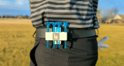 ProtoClip MINI 2 securely holding golf tees on a golfer's belt during a sunny day on the course.