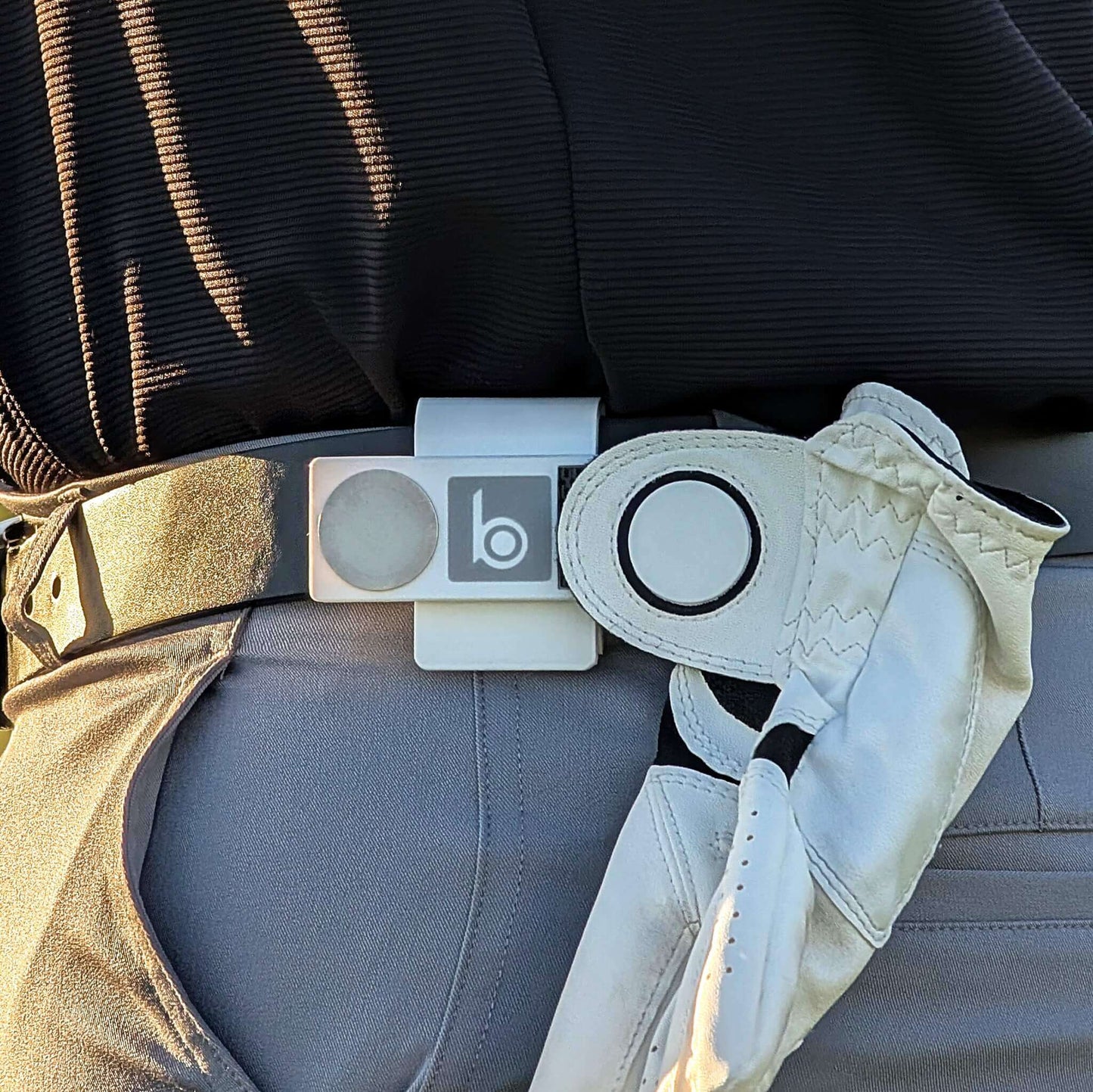 ProtoClip™ MINI 1 attached to a golfer's belt with a glove, showcasing its compact and lightweight design.