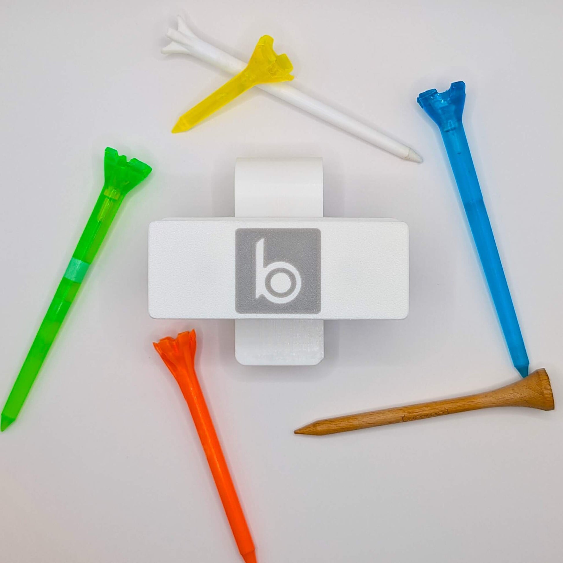 ProtoClip MINI 2 with colorful golf tees arranged around it, showcasing a compact design for golfers.