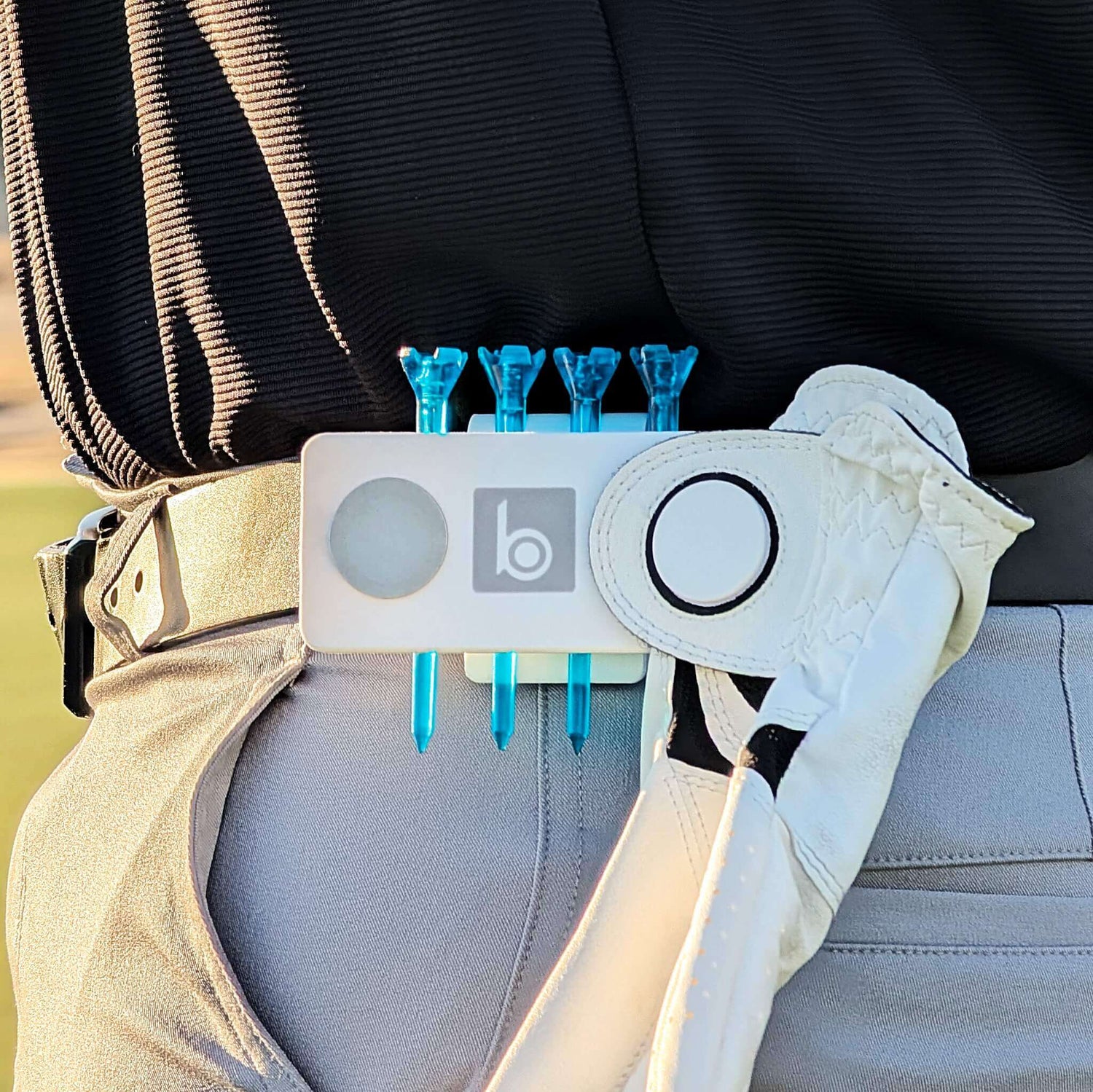 ProtoClip™ white golf utility clip with four blue golf tees, ball marker, and glove, attached to a belt.